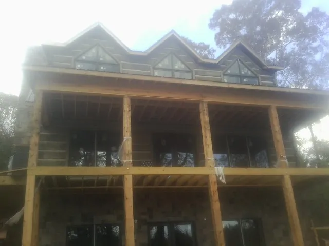 Dormers and porch framing on a large log home under construction — Roof Coating work by our crew in Orgas