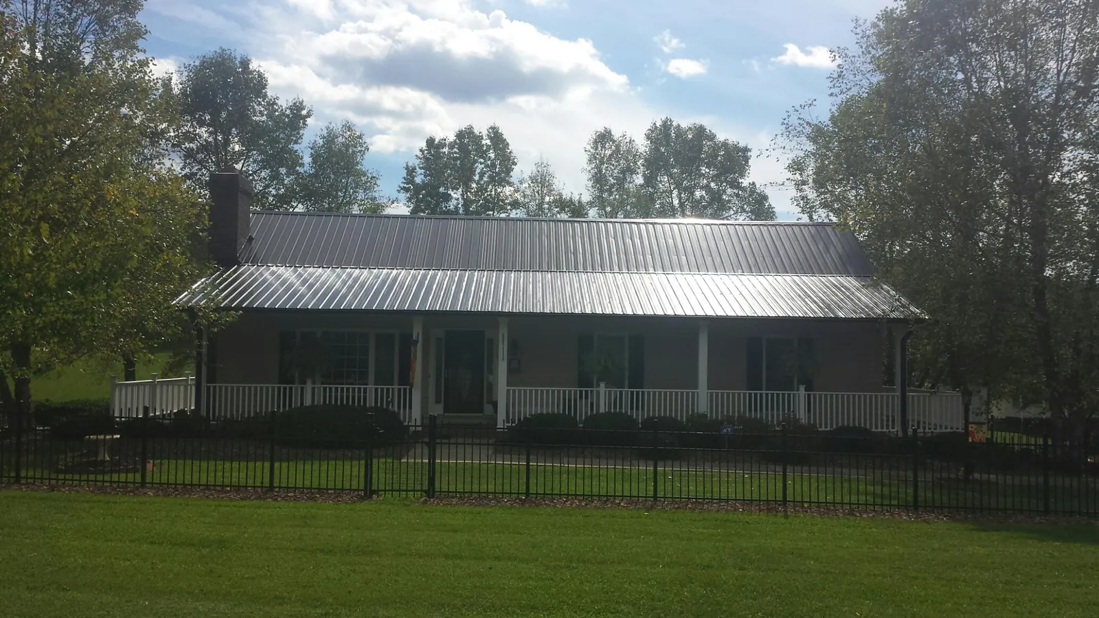 Gray metal roof on a brick ranch with a full width front porch — Gutter Guard Installation work by our crew in Orgas