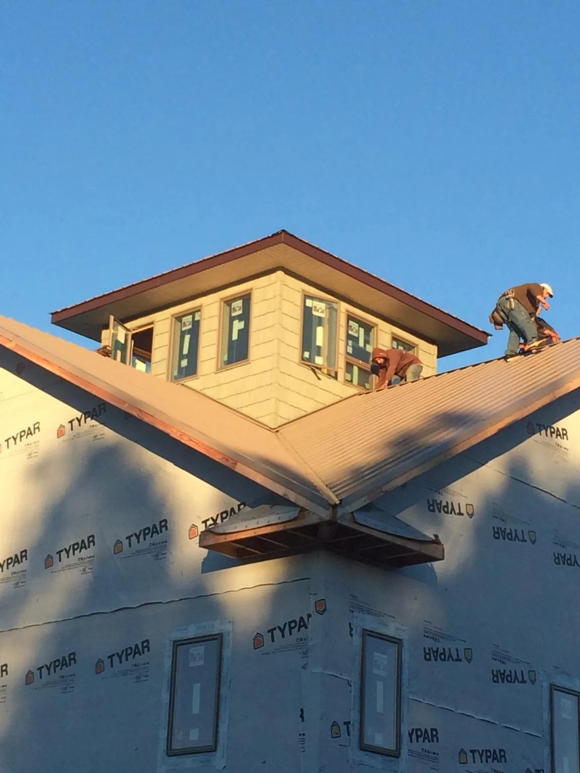 Roofers working around a rooftop cupola on a new metal roof at sunset — Roof Waterproofing in Orgas by Roofing Brothers